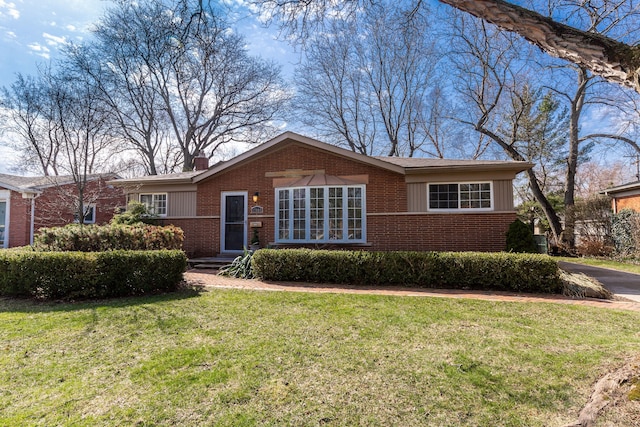 single story home featuring brick siding, a chimney, and a front lawn