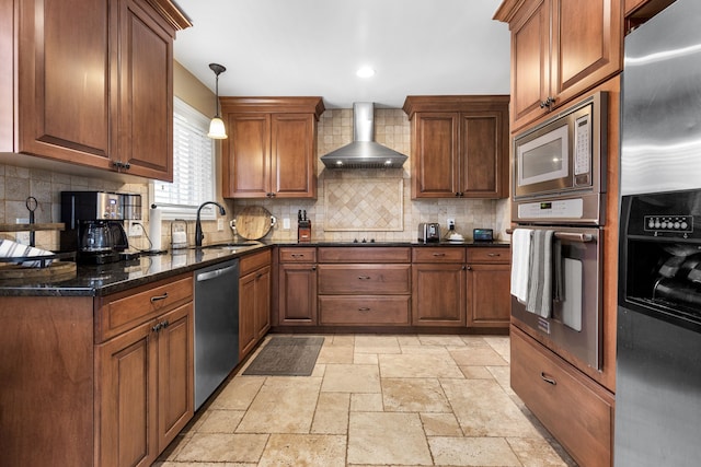 kitchen with tasteful backsplash, wall chimney range hood, stone tile floors, stainless steel appliances, and a sink