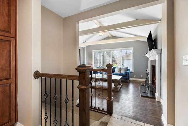 hall featuring lofted ceiling with beams, hardwood / wood-style flooring, an upstairs landing, and baseboards