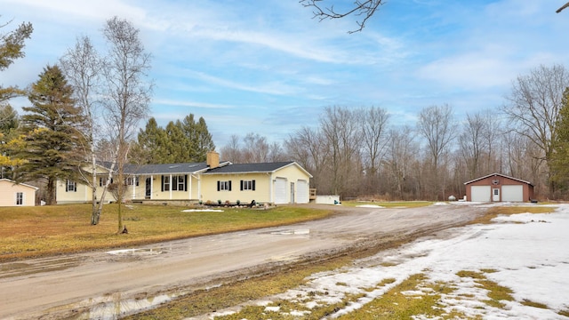 ranch-style house with a front yard, a chimney, a garage, an outdoor structure, and driveway