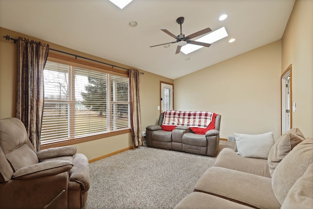 carpeted living area with vaulted ceiling with skylight, recessed lighting, a ceiling fan, and baseboards