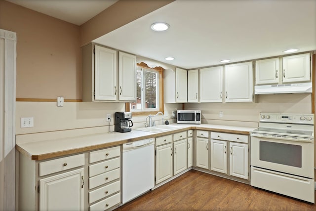 kitchen with dark wood-type flooring, under cabinet range hood, white appliances, white cabinetry, and a sink