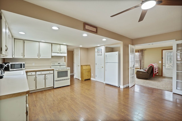 kitchen with white appliances, white cabinets, light countertops, and light wood-type flooring