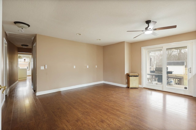 spare room featuring a textured ceiling, baseboards, dark wood-style flooring, and ceiling fan