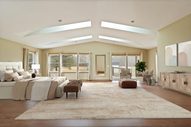 bedroom with lofted ceiling with skylight, wood finished floors, and access to outside