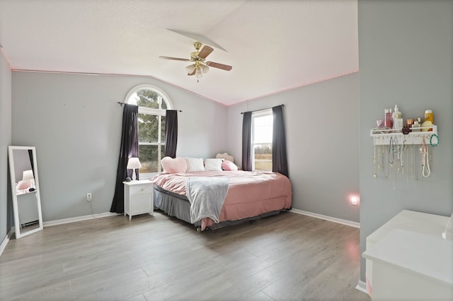 bedroom with vaulted ceiling, light wood-style flooring, baseboards, and ceiling fan