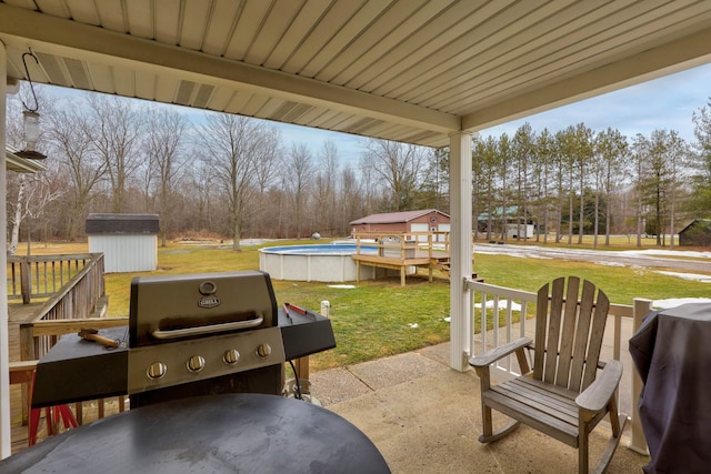 view of patio / terrace with an outdoor pool, a storage unit, an outbuilding, and area for grilling