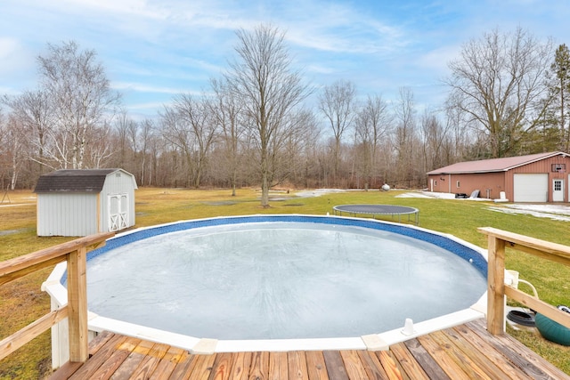 view of swimming pool with a storage unit, a yard, an outbuilding, and a trampoline