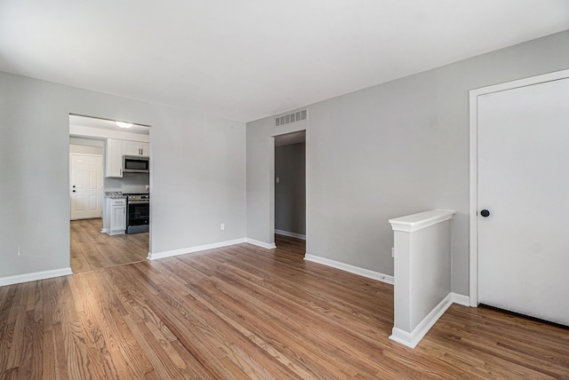 empty room featuring baseboards, visible vents, and light wood-type flooring