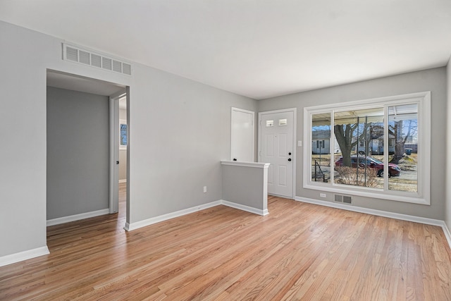 spare room featuring light wood-style floors, visible vents, and baseboards