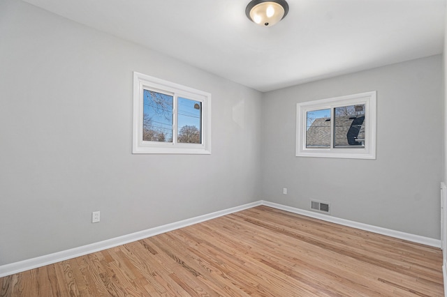 unfurnished room with baseboards, visible vents, and light wood-type flooring