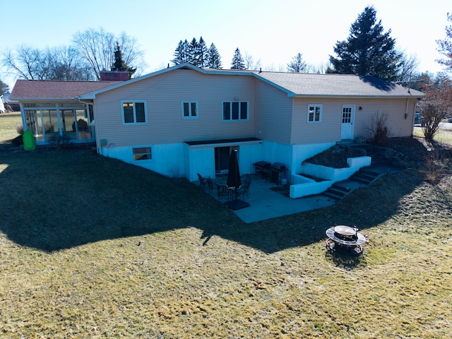 back of house featuring a patio, an outdoor fire pit, a yard, and a sunroom