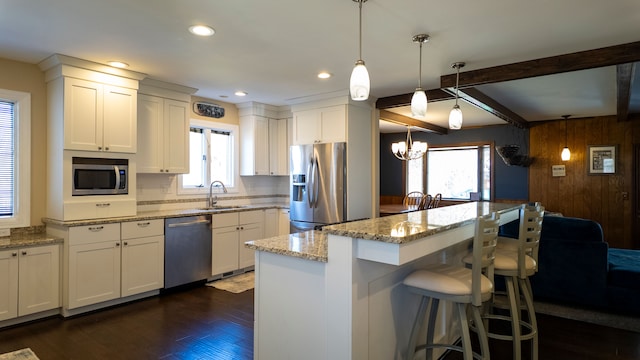 kitchen with dark wood-type flooring, a breakfast bar, a sink, appliances with stainless steel finishes, and light stone countertops