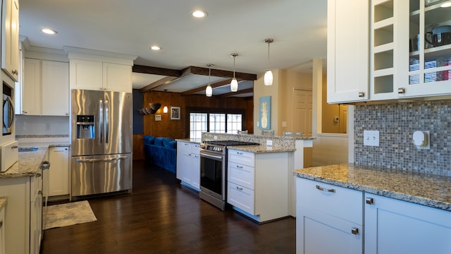 kitchen featuring wooden walls, light stone counters, dark wood-type flooring, appliances with stainless steel finishes, and white cabinetry