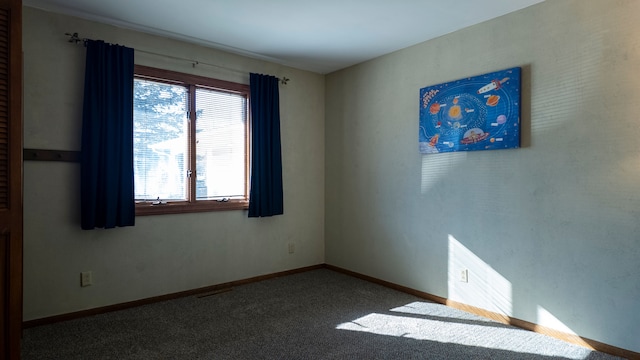 spare room featuring carpet and baseboards