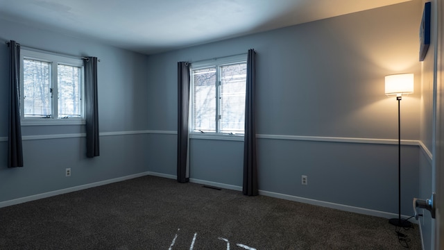 carpeted spare room with visible vents and baseboards