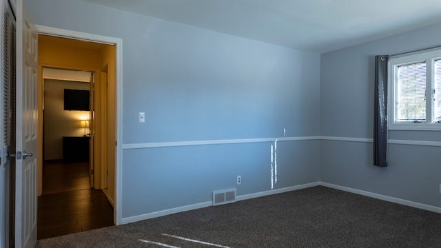 unfurnished room with visible vents, baseboards, and dark colored carpet