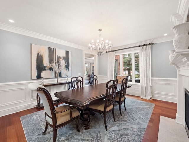 dining room with a notable chandelier, crown molding, a fireplace with flush hearth, and wood finished floors