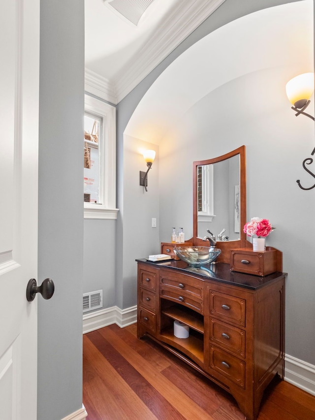 bathroom featuring visible vents, wood finished floors, crown molding, baseboards, and vanity