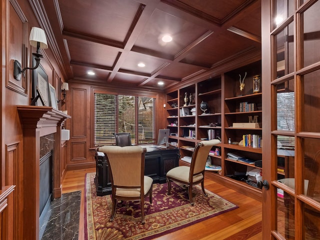 home office featuring wooden walls, coffered ceiling, a fireplace, ornamental molding, and dark wood-type flooring