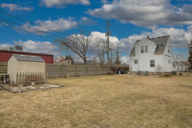 view of yard featuring a storage unit, an outdoor structure, a fenced backyard, and cooling unit