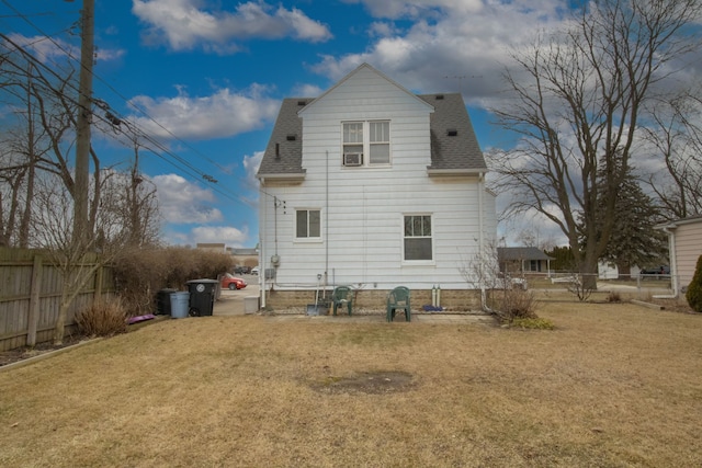 back of house with a shingled roof, a fenced backyard, and a yard