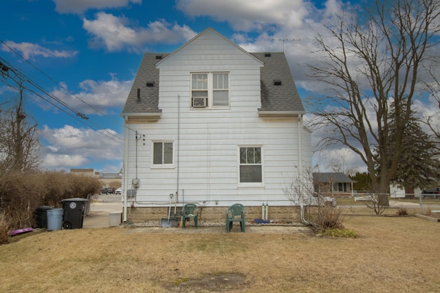 rear view of house featuring roof with shingles, a yard, and fence