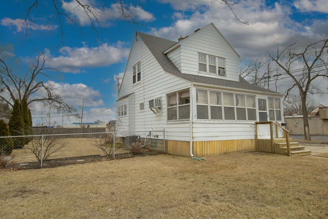 back of property with a sunroom, a shingled roof, fence, and a yard