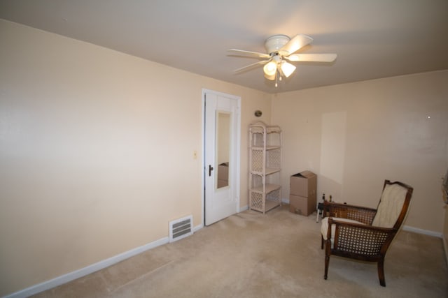 living area featuring a ceiling fan, light colored carpet, visible vents, and baseboards