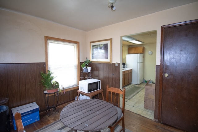 dining space with wood walls, wainscoting, and wood finished floors