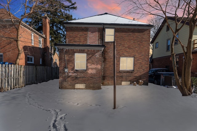 snow covered house with crawl space, fence, and brick siding