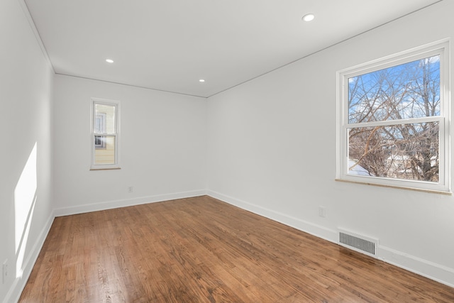 unfurnished room featuring a wealth of natural light, wood finished floors, visible vents, and baseboards