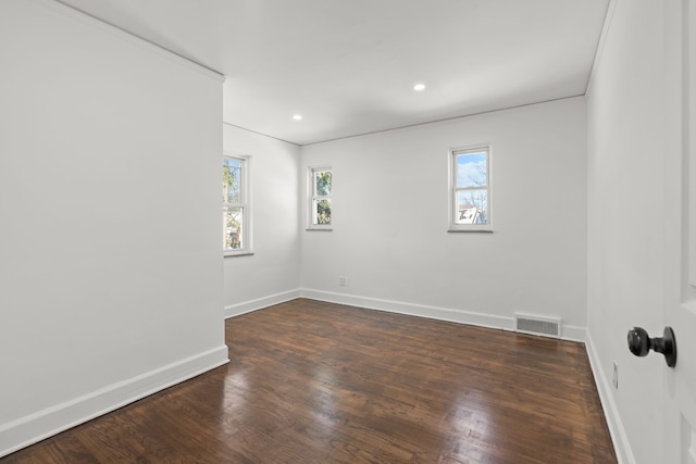 unfurnished room with a wealth of natural light, visible vents, baseboards, and wood finished floors