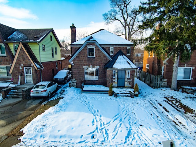 view of front of property with driveway, a chimney, fence, and brick siding