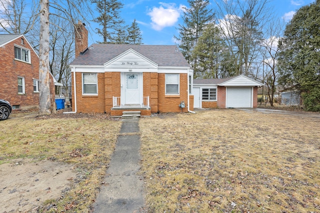 view of front facade featuring brick siding, a chimney, an attached garage, and a front yard