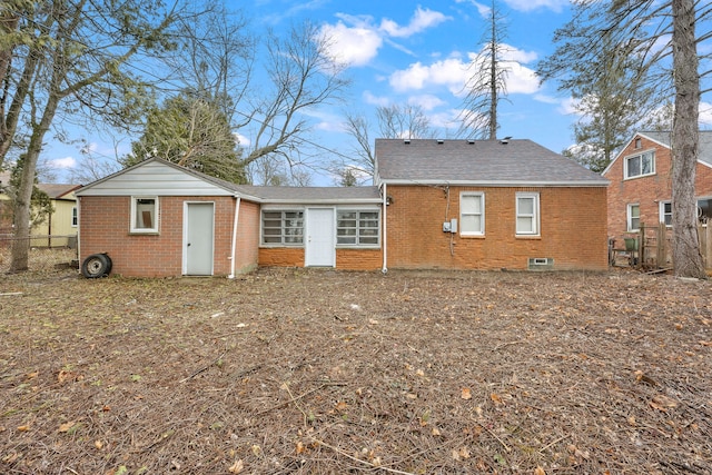 rear view of house featuring brick siding and fence