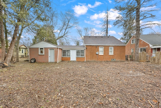 rear view of house with brick siding and fence