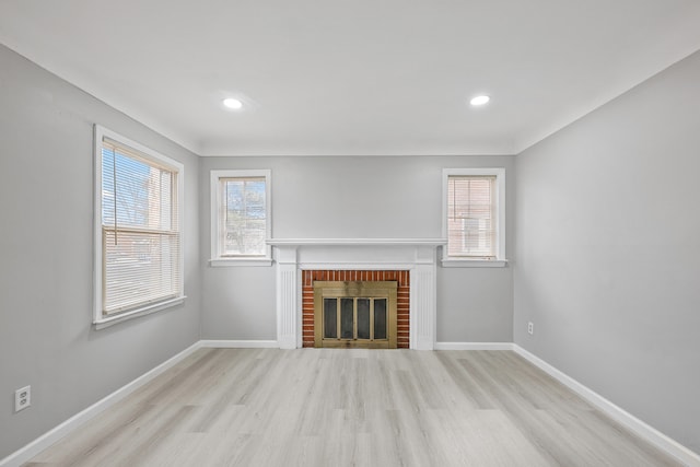 unfurnished living room featuring recessed lighting, a brick fireplace, baseboards, and wood finished floors