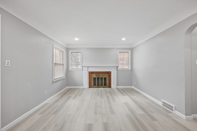 unfurnished living room with a wealth of natural light, visible vents, a fireplace, and baseboards