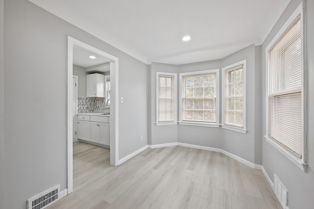 unfurnished dining area featuring light wood finished floors, visible vents, and baseboards