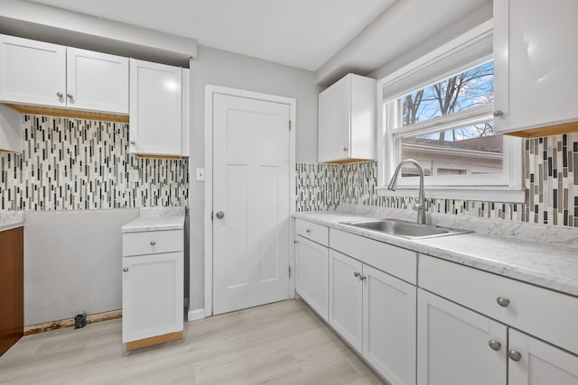 kitchen featuring white cabinetry, decorative backsplash, and a sink