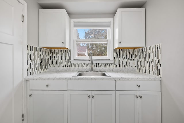 kitchen with tasteful backsplash, a sink, and white cabinetry