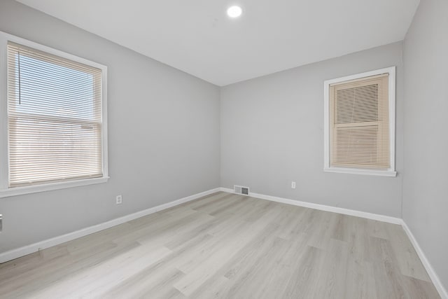 unfurnished room with light wood finished floors, visible vents, and baseboards