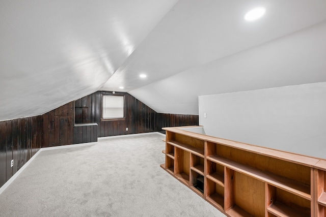 bonus room featuring lofted ceiling, wood walls, carpet, and baseboards