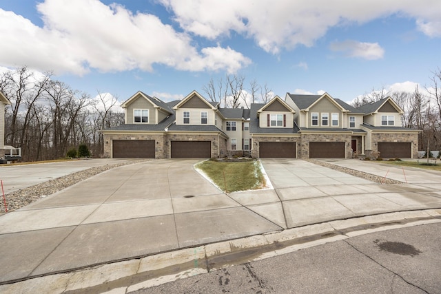 view of front facade with driveway, stone siding, and an attached garage