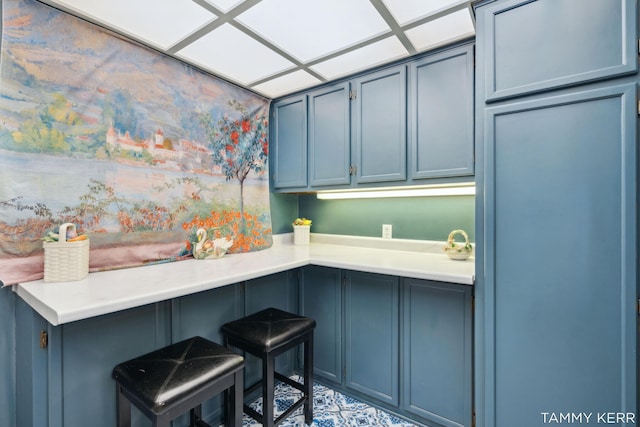 kitchen featuring blue cabinets, light countertops, and a breakfast bar area