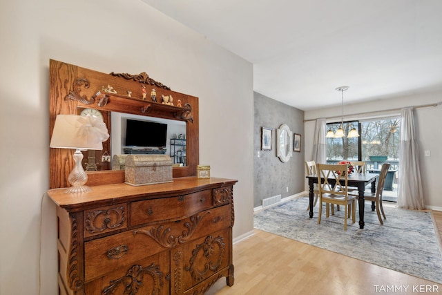 dining area featuring light wood-type flooring, baseboards, visible vents, and a notable chandelier