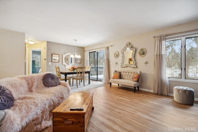 living area featuring light wood-type flooring, an inviting chandelier, and baseboards