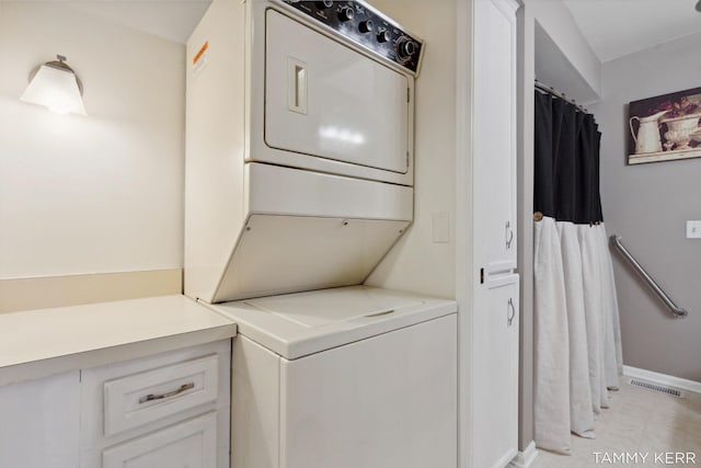 washroom with visible vents, laundry area, stacked washer and clothes dryer, and baseboards