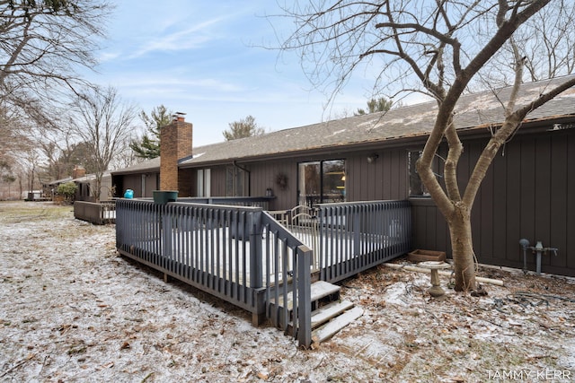 rear view of property with a shingled roof, a chimney, and a wooden deck